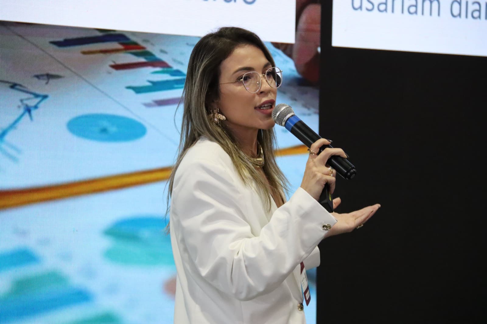 Camila Fraga apresentando, microfone na mão